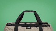 Beige duffel bag with black handles and zipper, featuring a "norda by Dyneema" label.