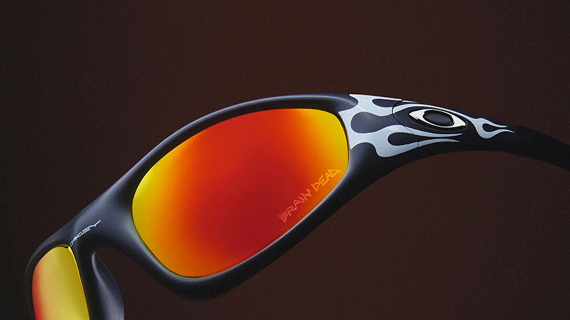 Black Oakley sunglasses with red-orange mirrored lenses and white flame design on the frame.