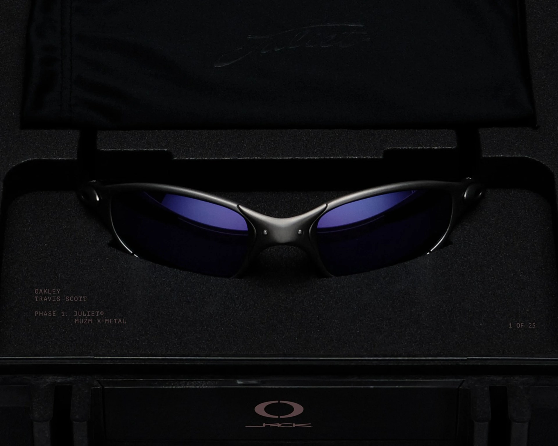 Black Oakley sunglasses with dark purple lenses in a black foam-lined case with Oakley and Travis Scott branding.
