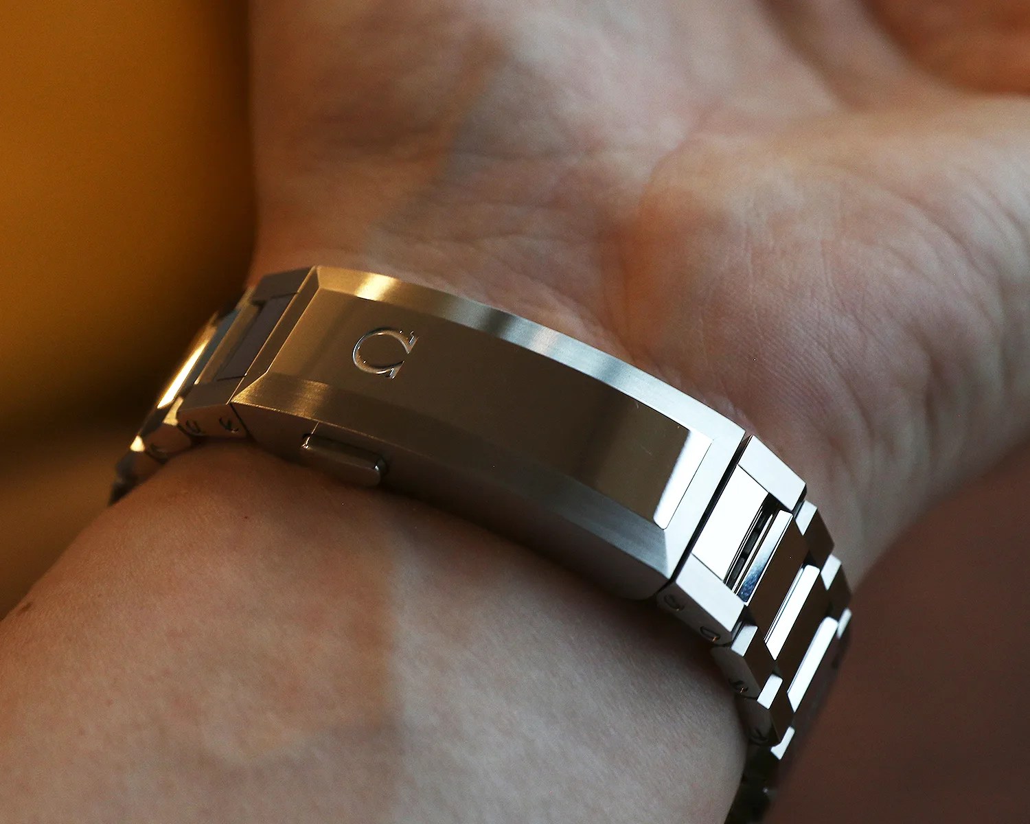 Close-up of a silver metal watch clasp with an Omega logo on a wrist.