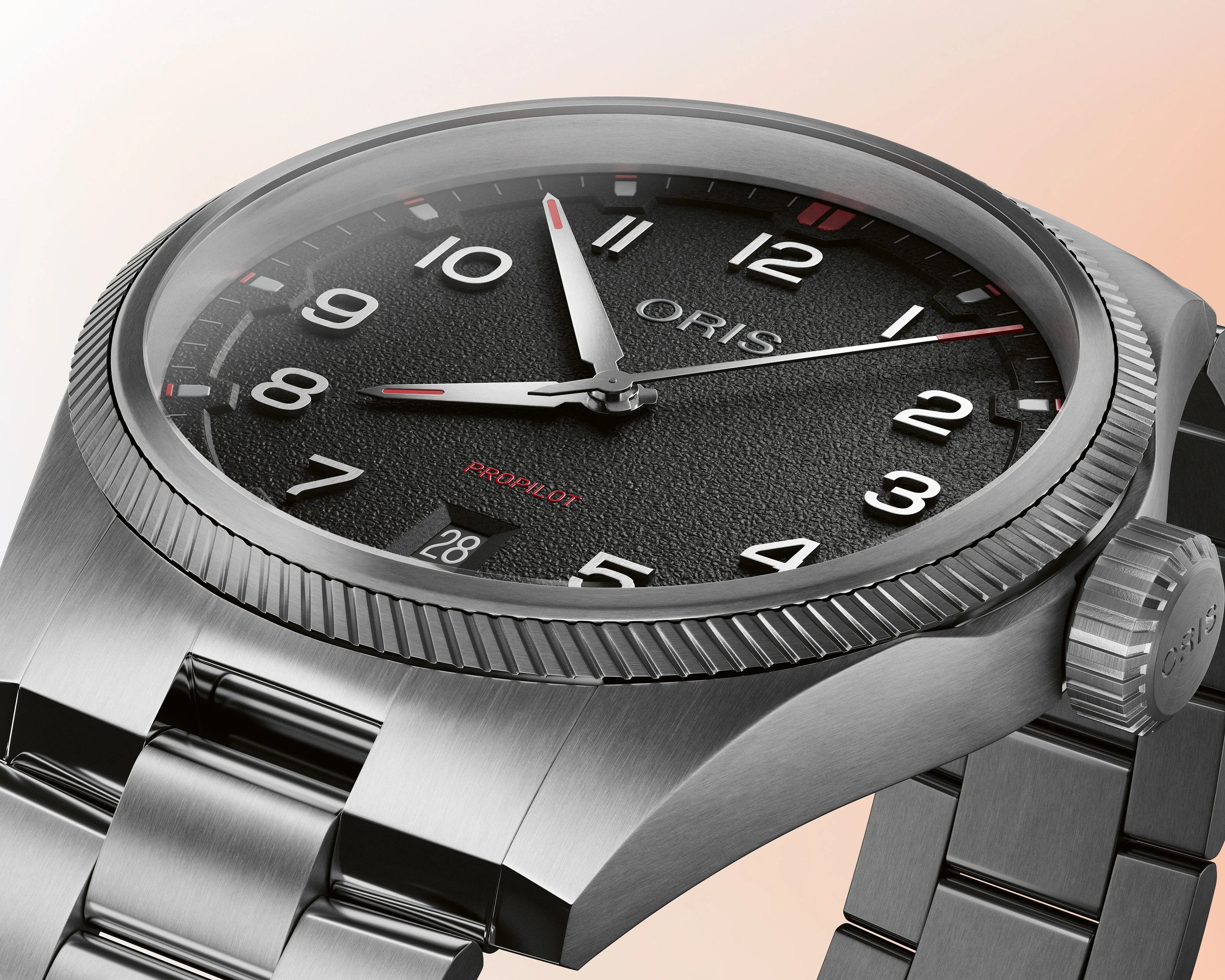 Close-up of a stainless steel Oris ProPilot watch with a textured black dial, white numerals, red accents, and a date window at 6 o'clock.