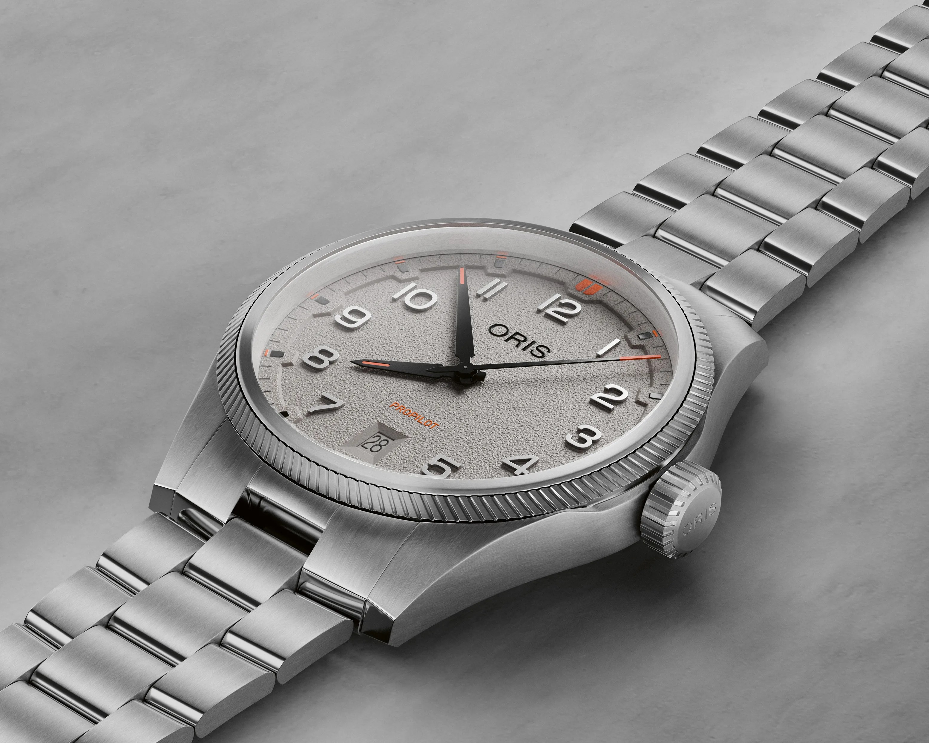 Silver stainless steel Oris ProPilot wristwatch with textured light gray dial and orange accents on a matching metal bracelet.
