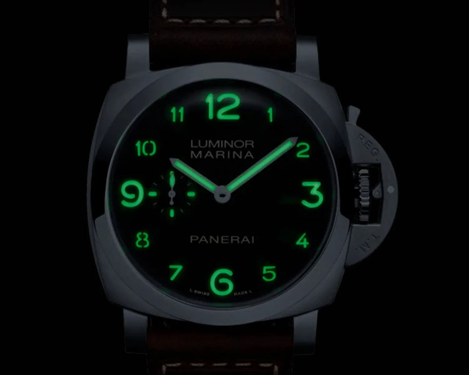Panerai Luminor Marina watch face glowing green in the dark with luminous numerals and hands.