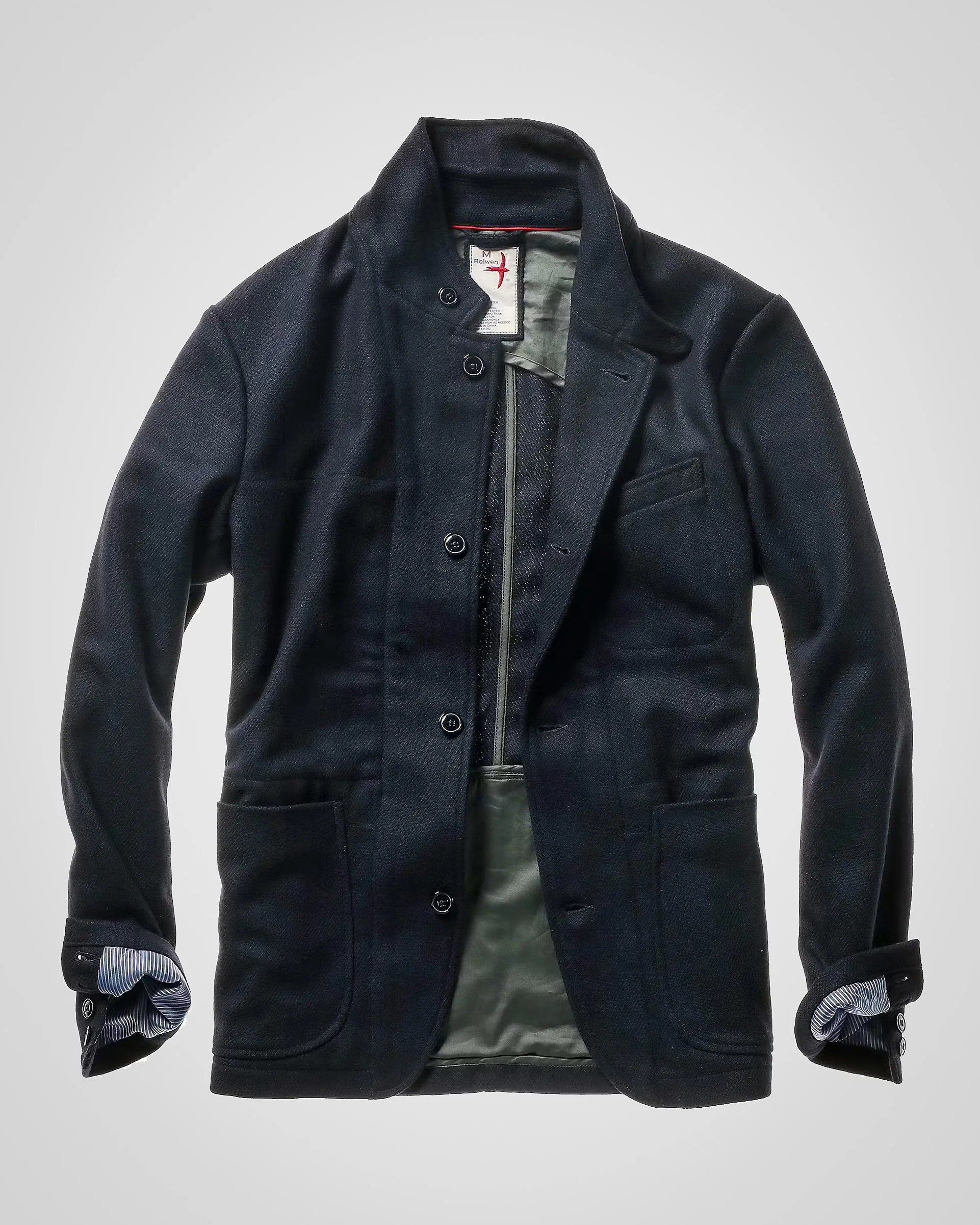 Black wool blazer with button closure and striped shirt cuffs visible inside sleeves.