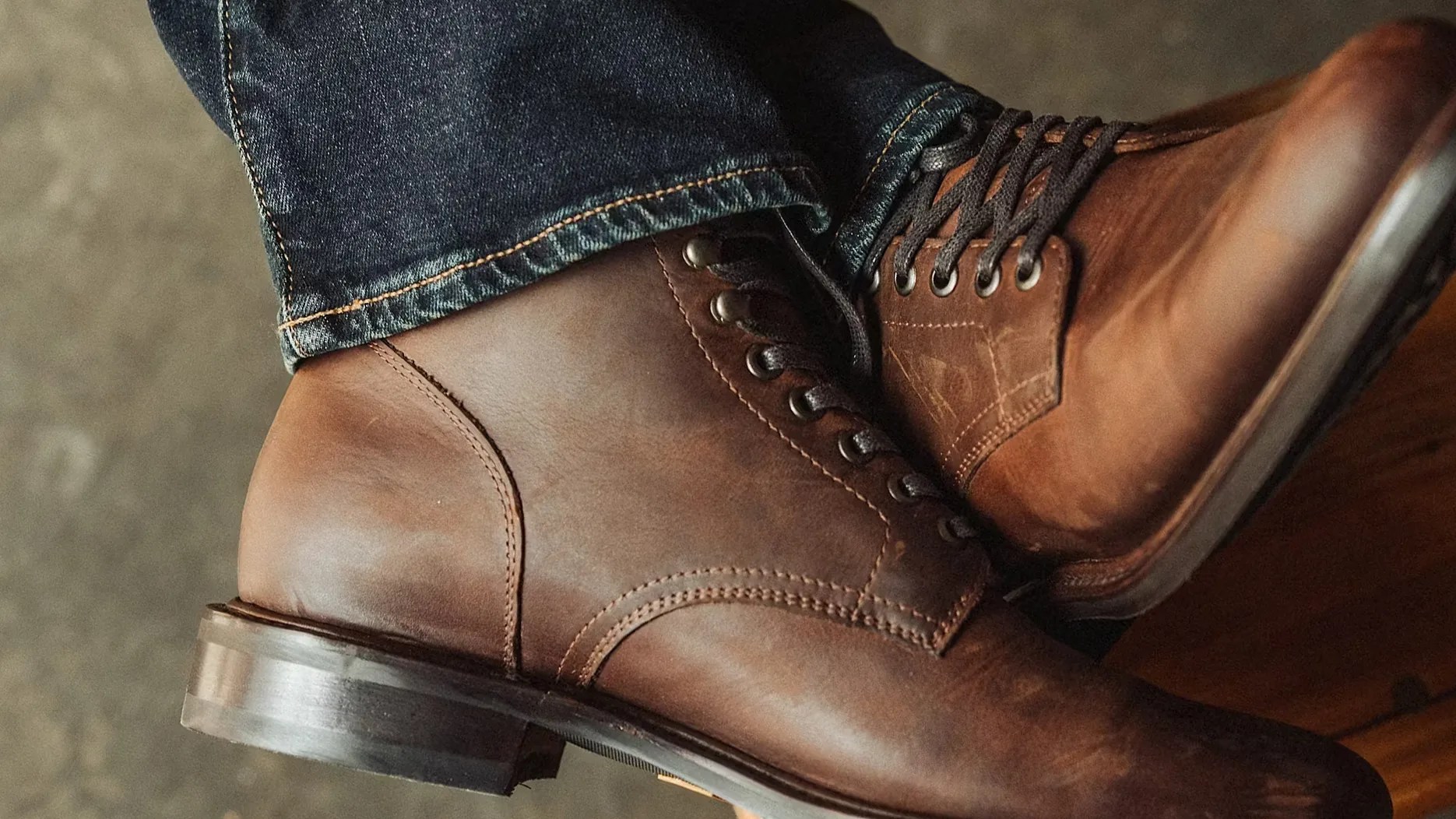 Brown leather lace-up boots worn with dark blue denim jeans.