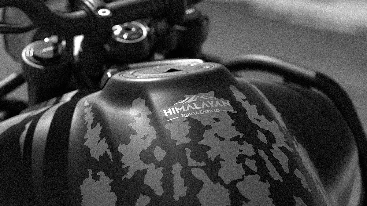 Close-up of a Royal Enfield Himalayan motorcycle fuel tank with a camouflage pattern.