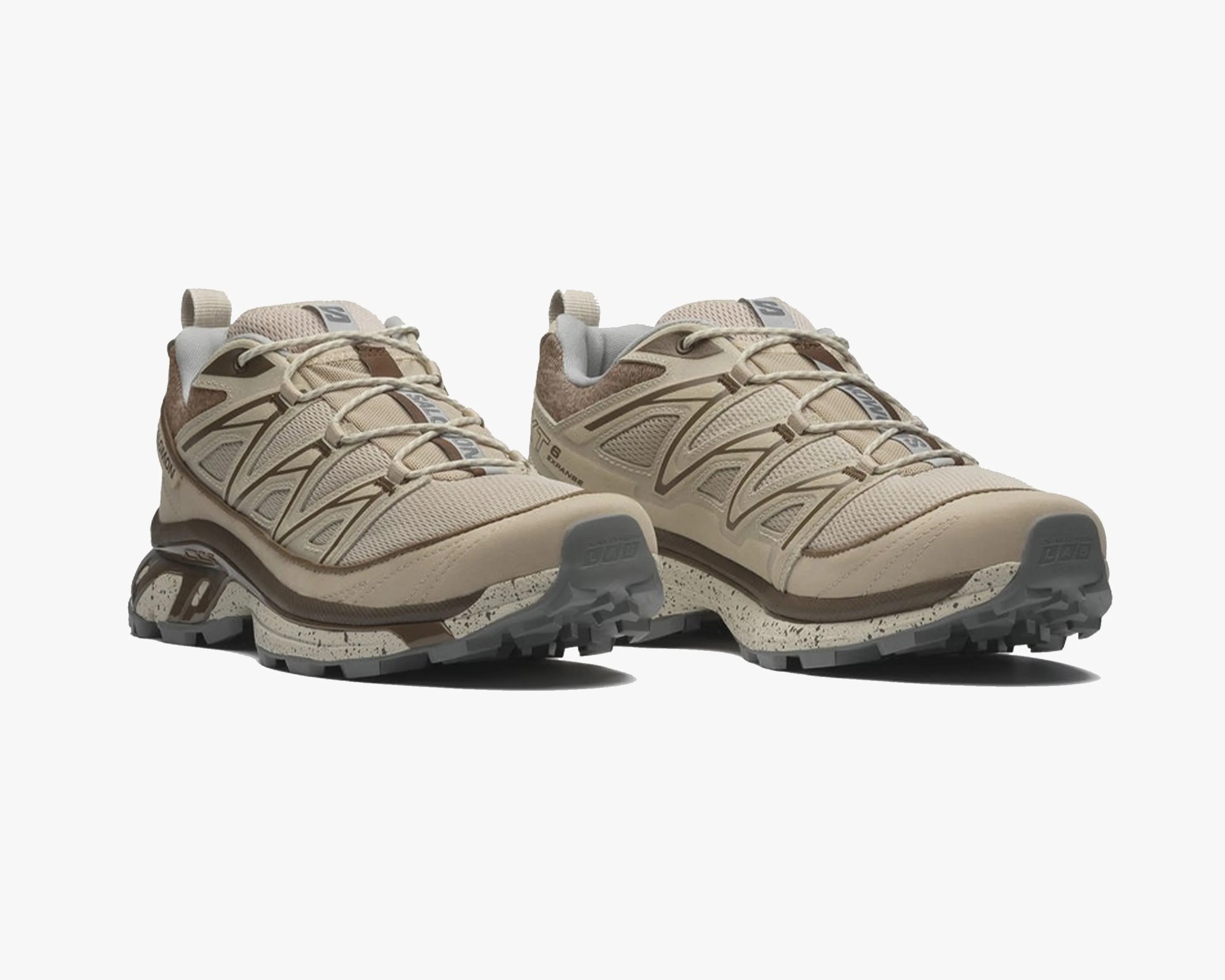 Pair of beige and brown trail running shoes with mesh upper and speckled midsole on a white background.