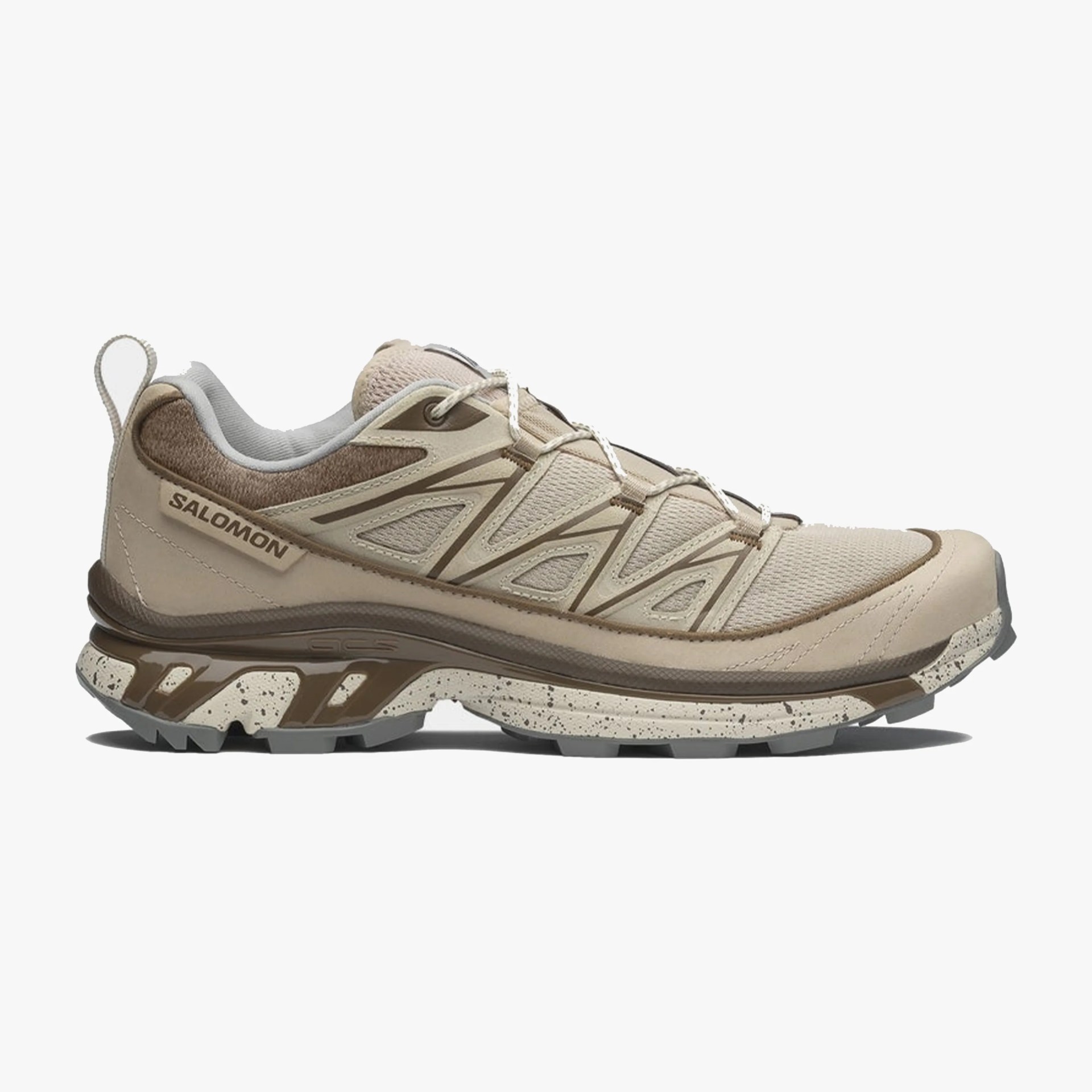 Beige and brown Salomon trail running shoe with speckled sole and mesh upper.