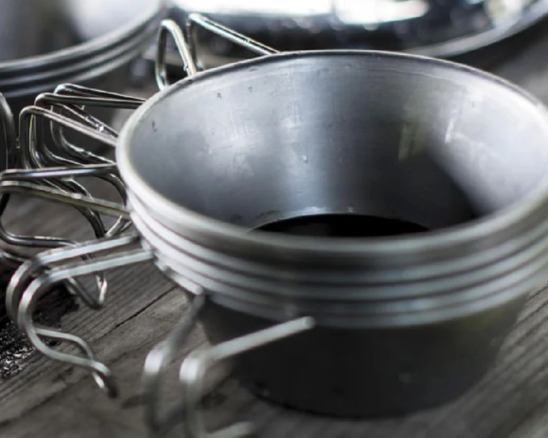 Stack of metal measuring cups with handles on a wooden surface.