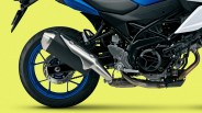 Rear section of a Suzuki motorcycle showing blue alloy wheel, exhaust pipe, and engine components against a yellow background.