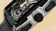 Close-up of a luxury watch with a black and silver case, black dial with gold and white hands, and a black crown.