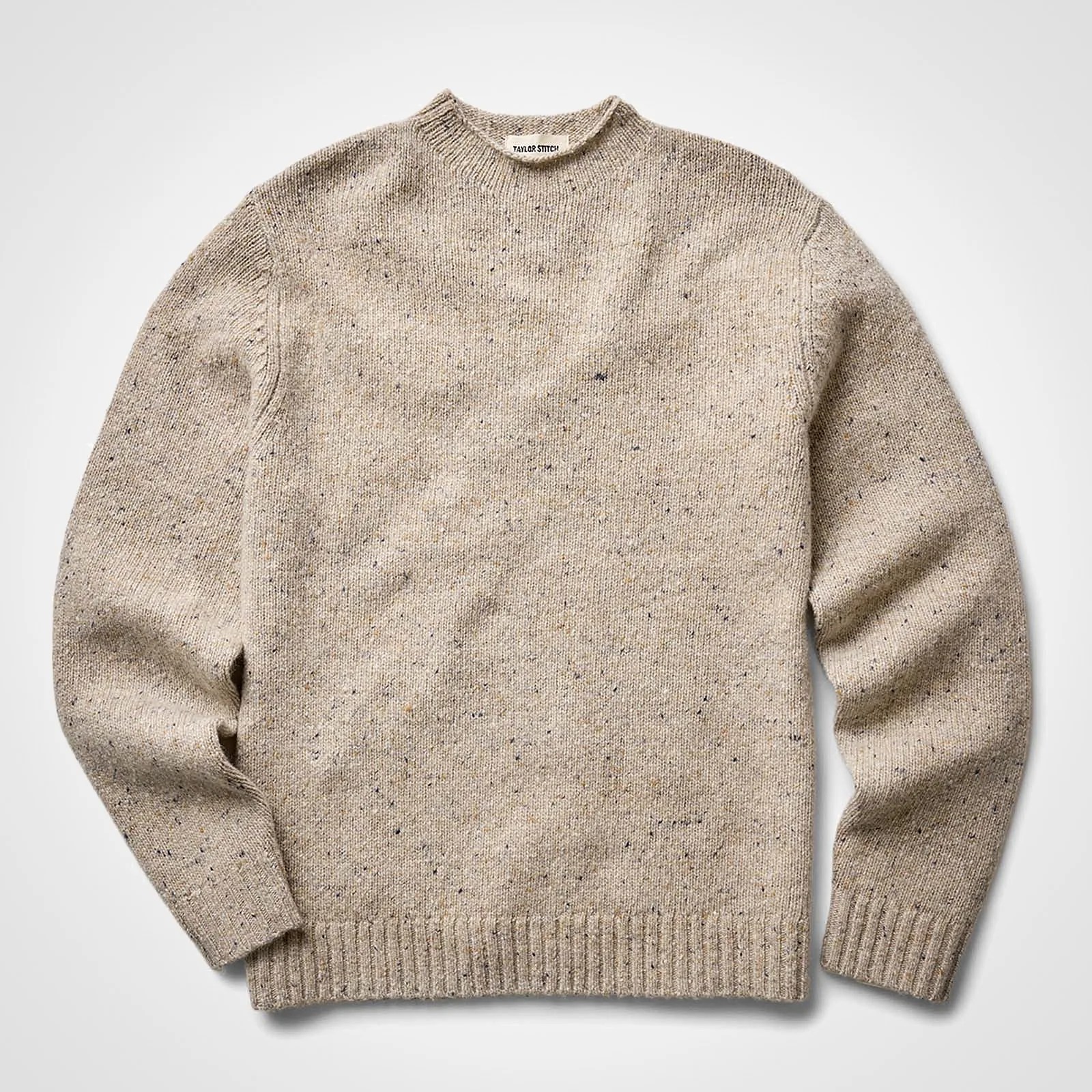 Beige speckled knit crewneck sweater with ribbed cuffs and hem laid flat on a white background.
