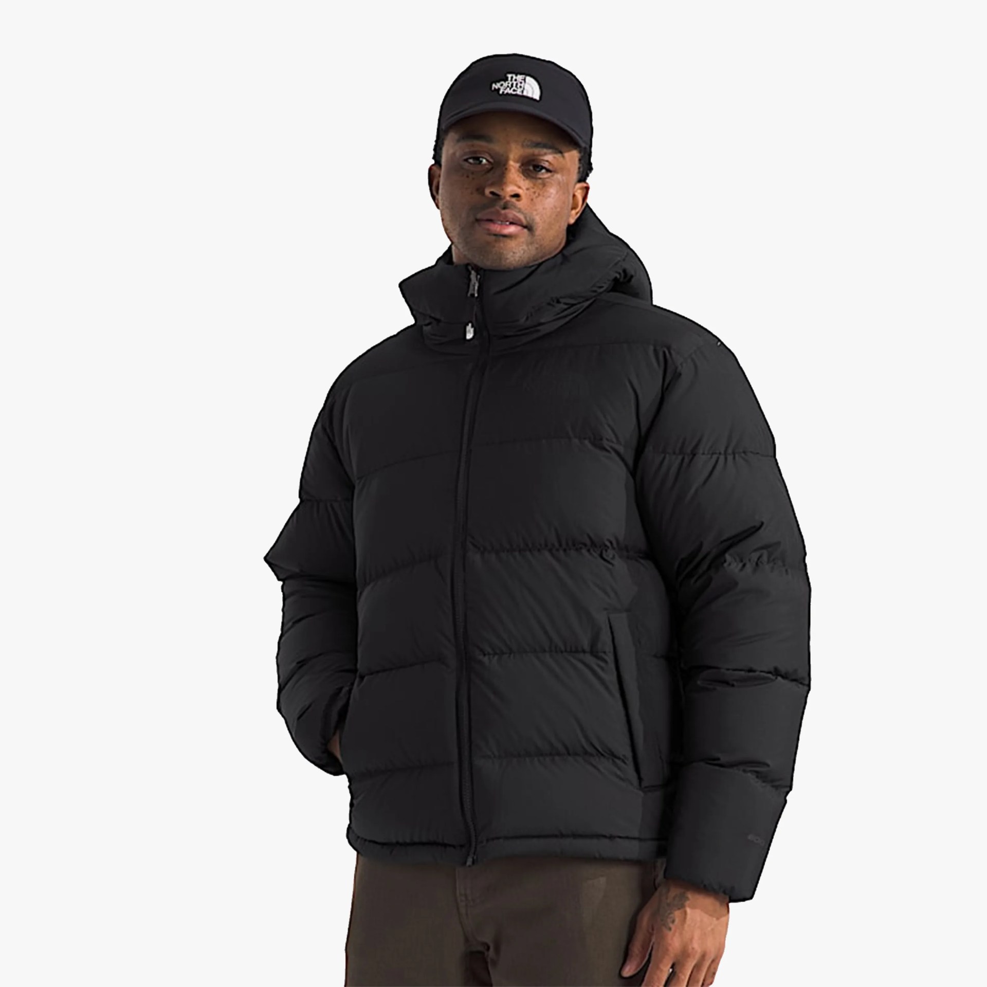 Black puffer jacket with hood worn by a person also wearing a black cap with The North Face logo.