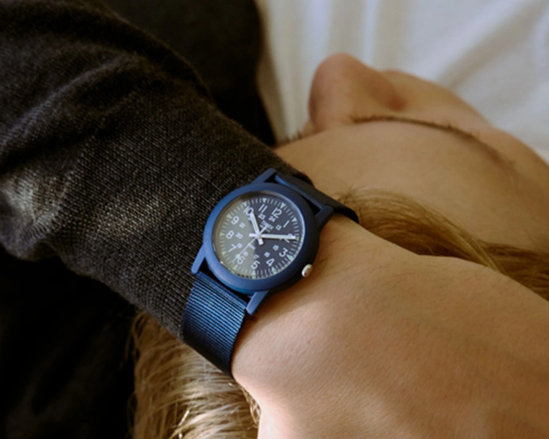 Black wristwatch with white numerals and a black nylon strap worn on a wrist.
