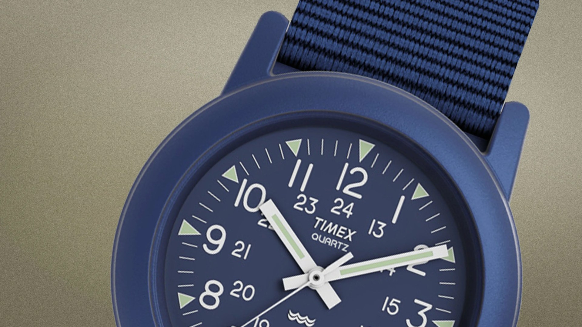 Close-up of a blue Timex quartz watch with white and green hands and a blue fabric strap.