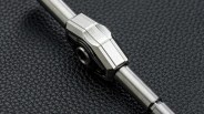 Close-up of a metallic watch crown and case side on a textured black surface.