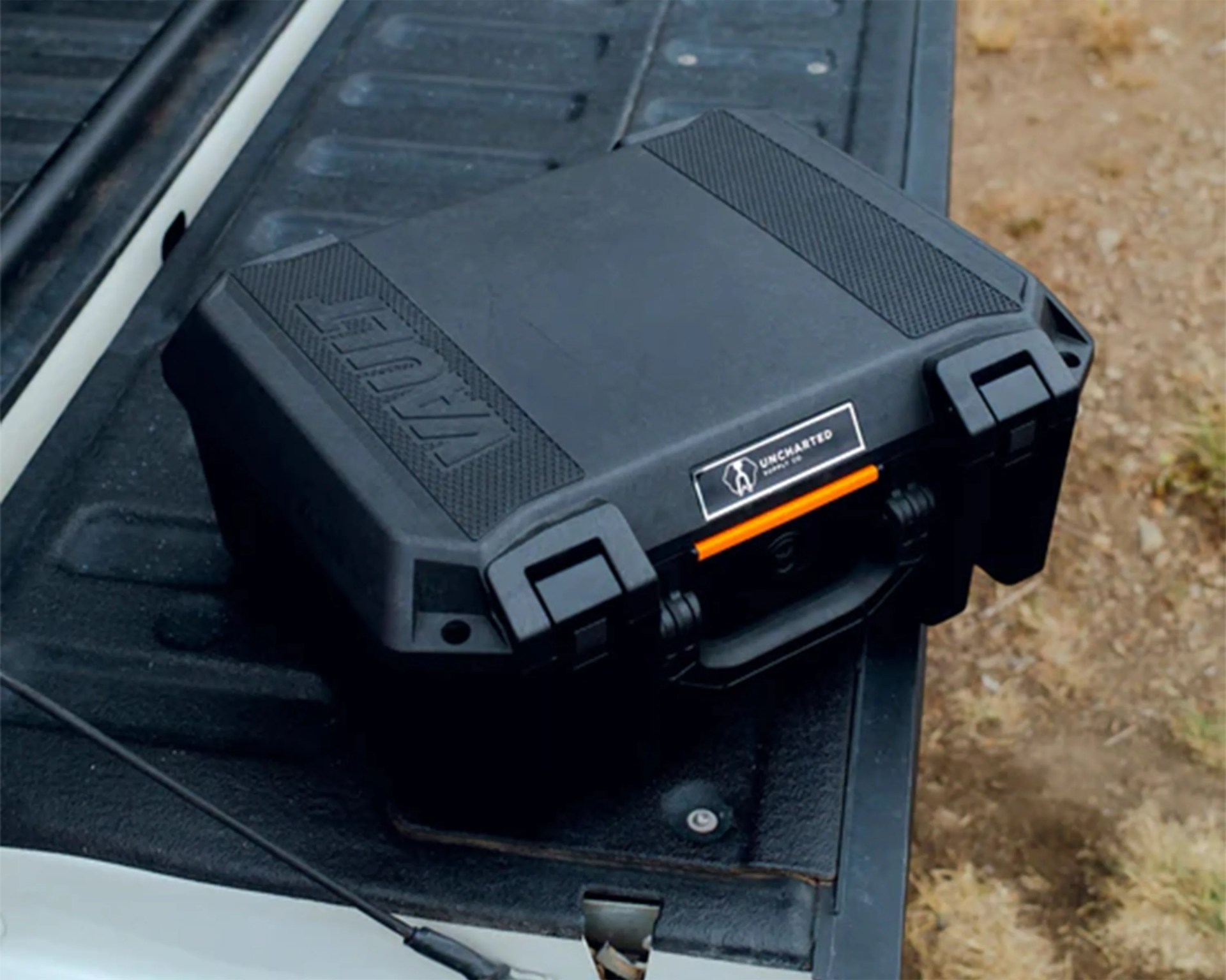Black rugged Vault protective case with latches and handle on a truck bed.