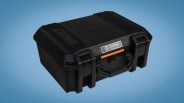 Black rugged hard plastic protective case with latches and an orange-accented handle on a blue background.