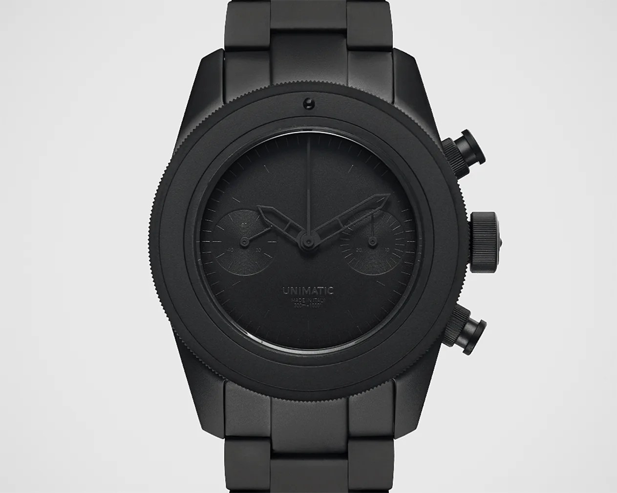 Matte black Unimatic wristwatch with chronograph subdials and metal link bracelet.