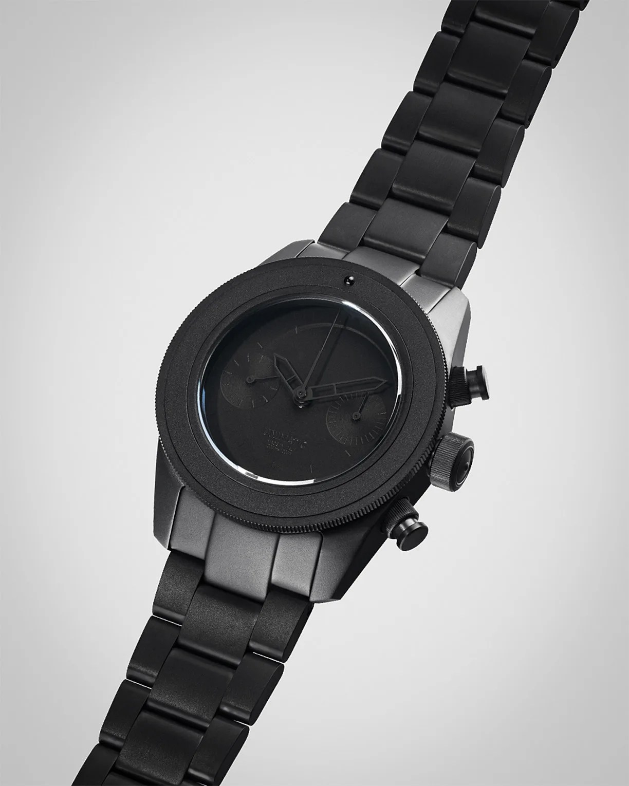 Matte black metal wristwatch with a round face, black dial, and black metal link bracelet.