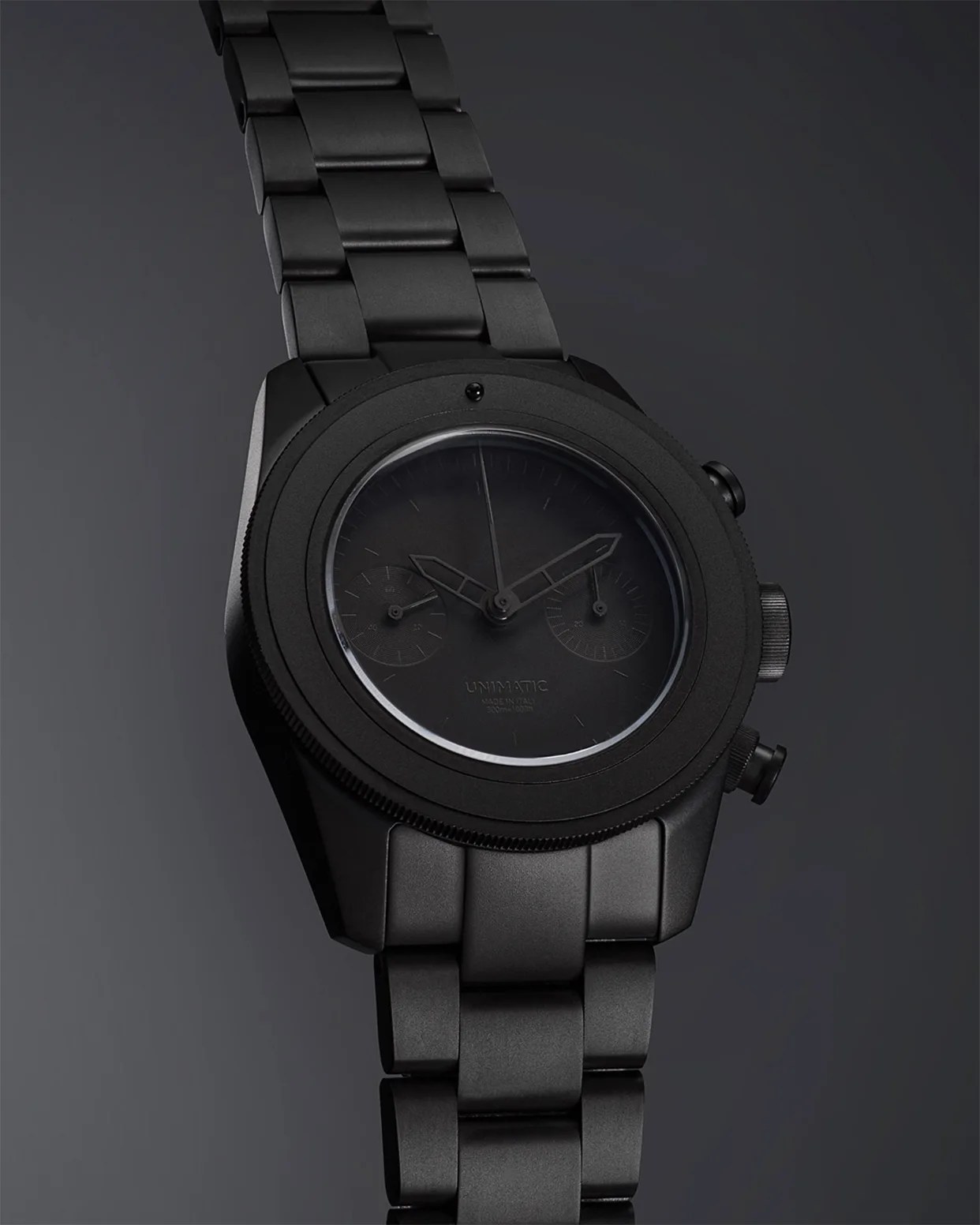 Matte black metal wristwatch with a black dial and chronograph subdials on a matching black metal link bracelet.