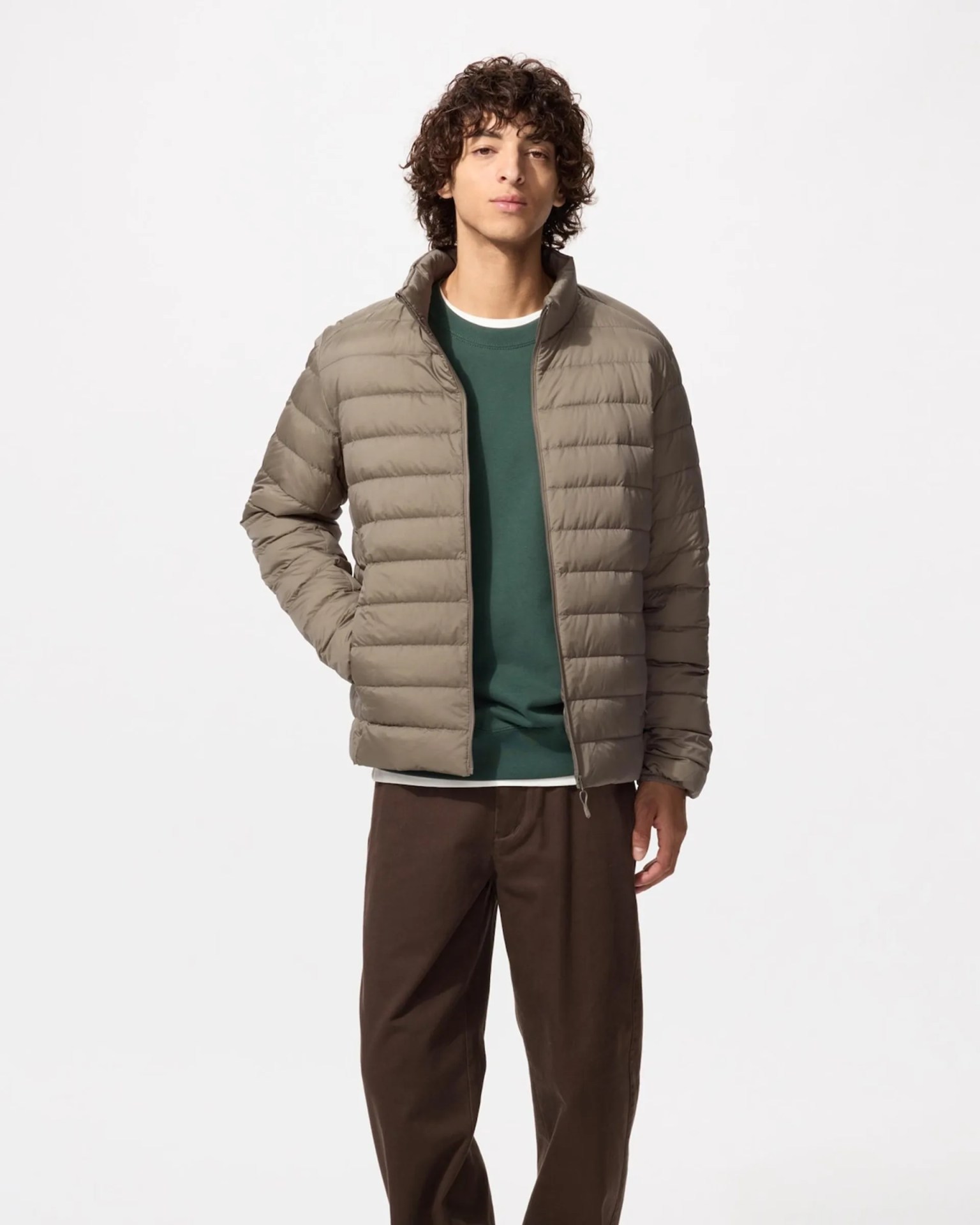 Taupe quilted puffer jacket worn over a green sweatshirt and brown pants.