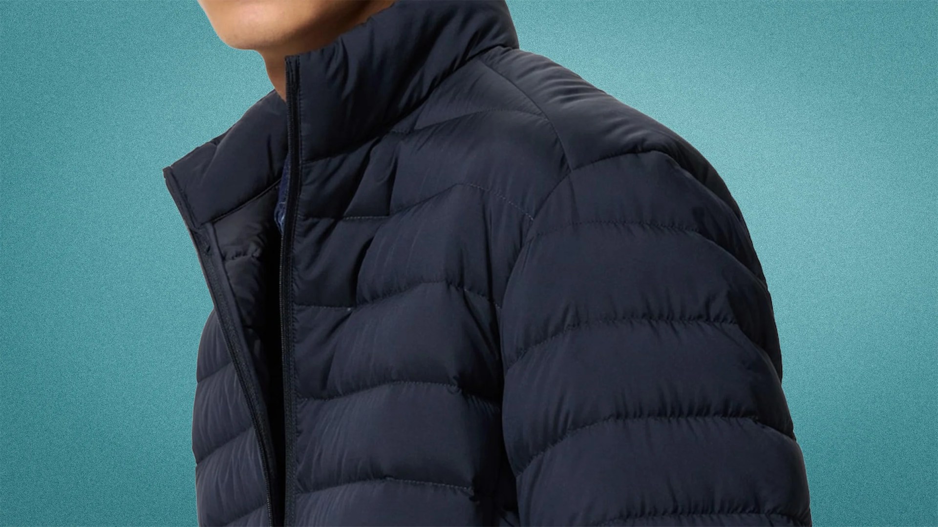 Navy blue quilted puffer jacket with a high collar and front zipper worn by a person.