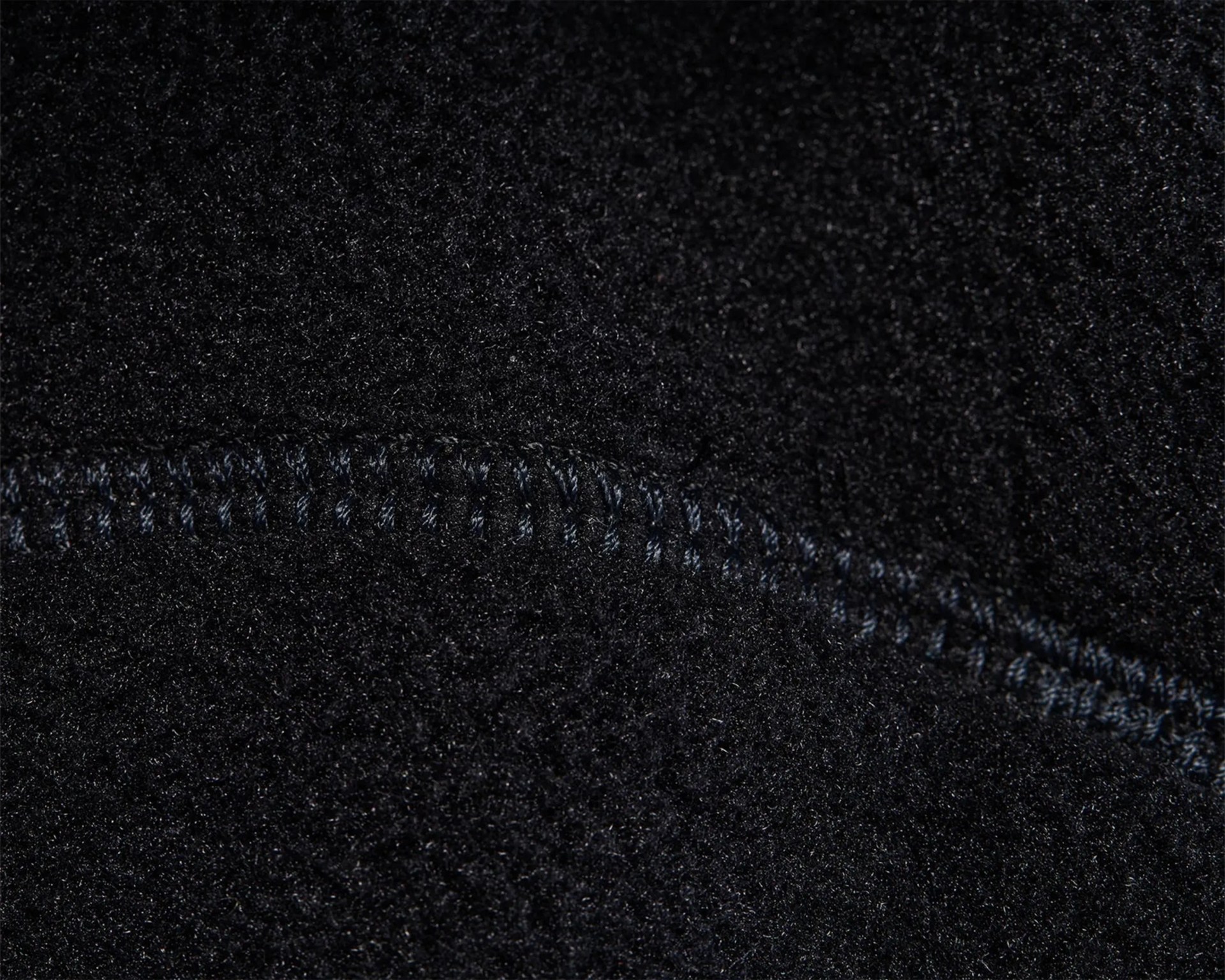 Close-up of black fleece fabric with visible stitching seam.