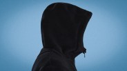 Black fleece hood with a front zipper against a blue background.