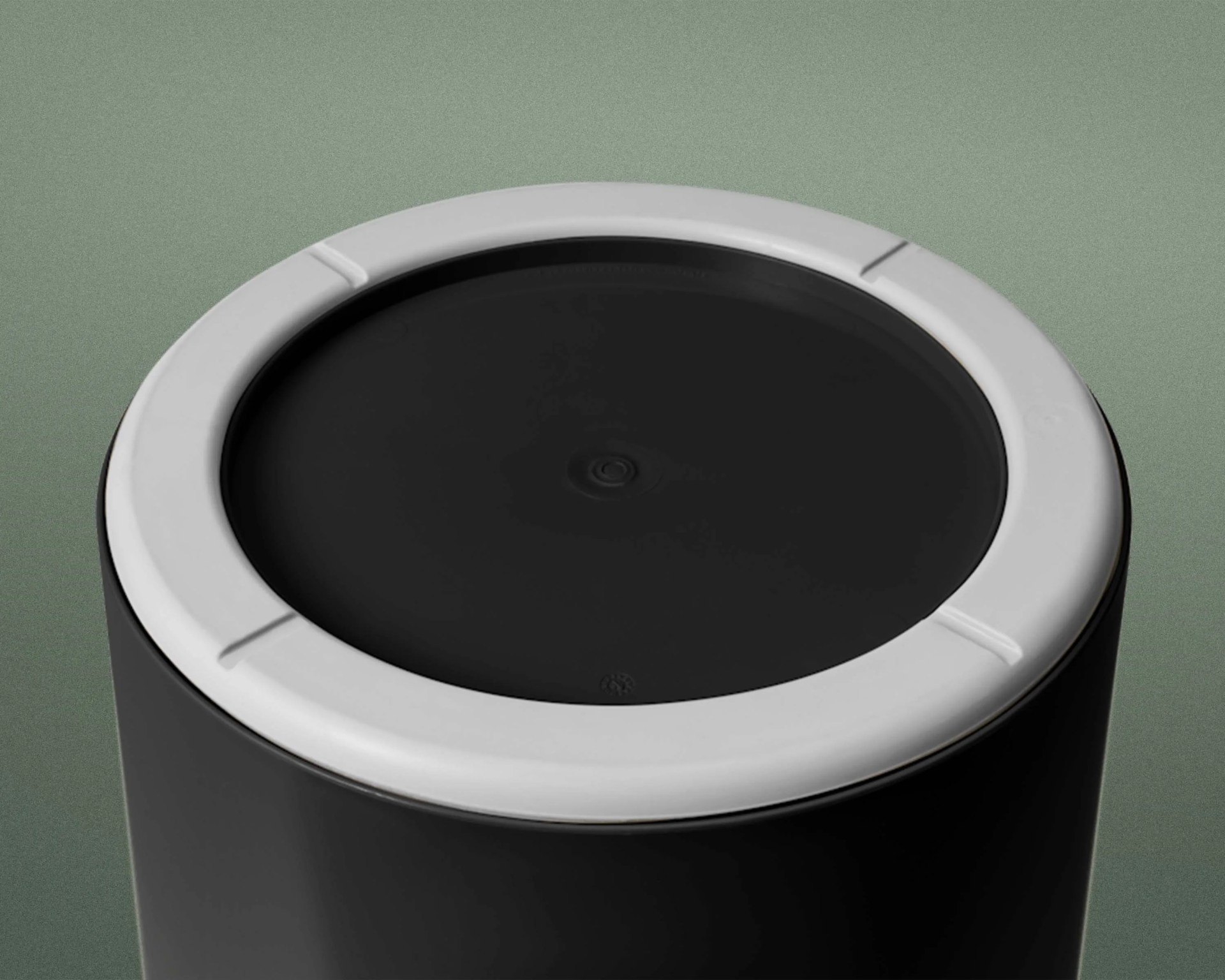 Top view of a black cylindrical object with a white circular rim on a green background.
