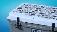 Gray YETI cooler with a light blue lid featuring a black and gray camouflage pattern and black latches.