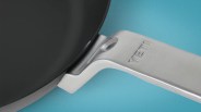 Close-up of a black YETI frying pan with a silver metal handle on a blue background.