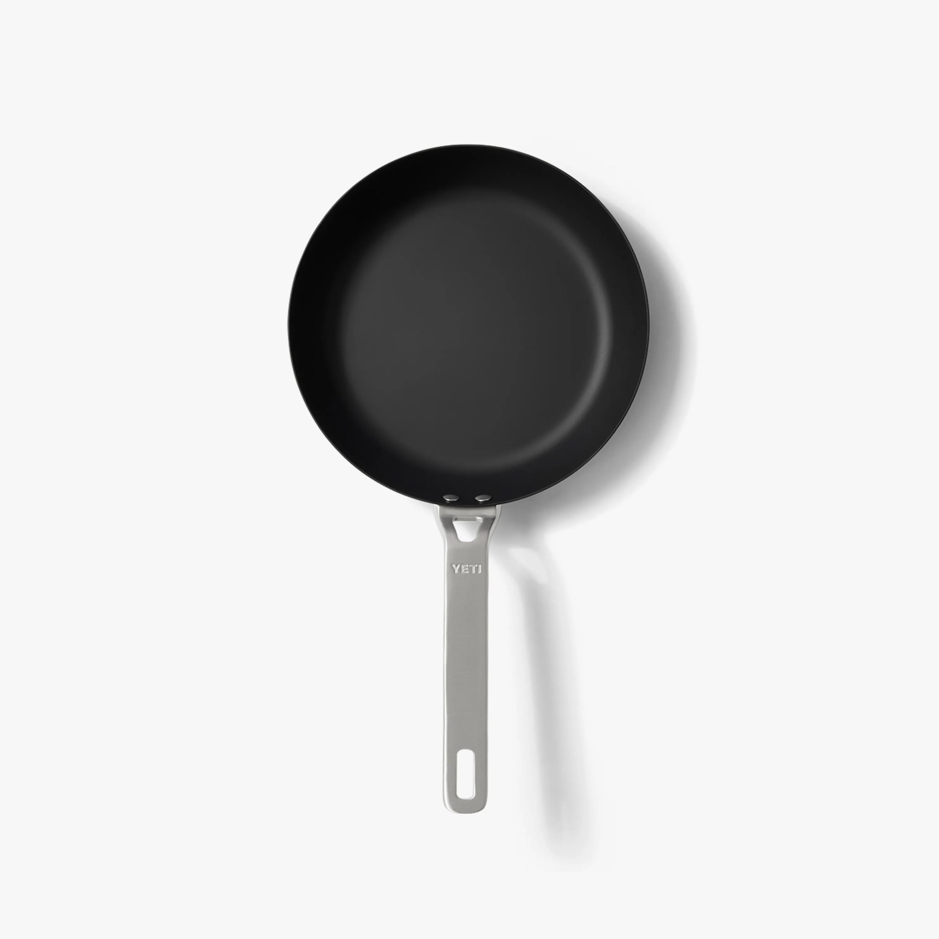 Black nonstick frying pan with silver metal handle engraved with "YETI" on a white background.