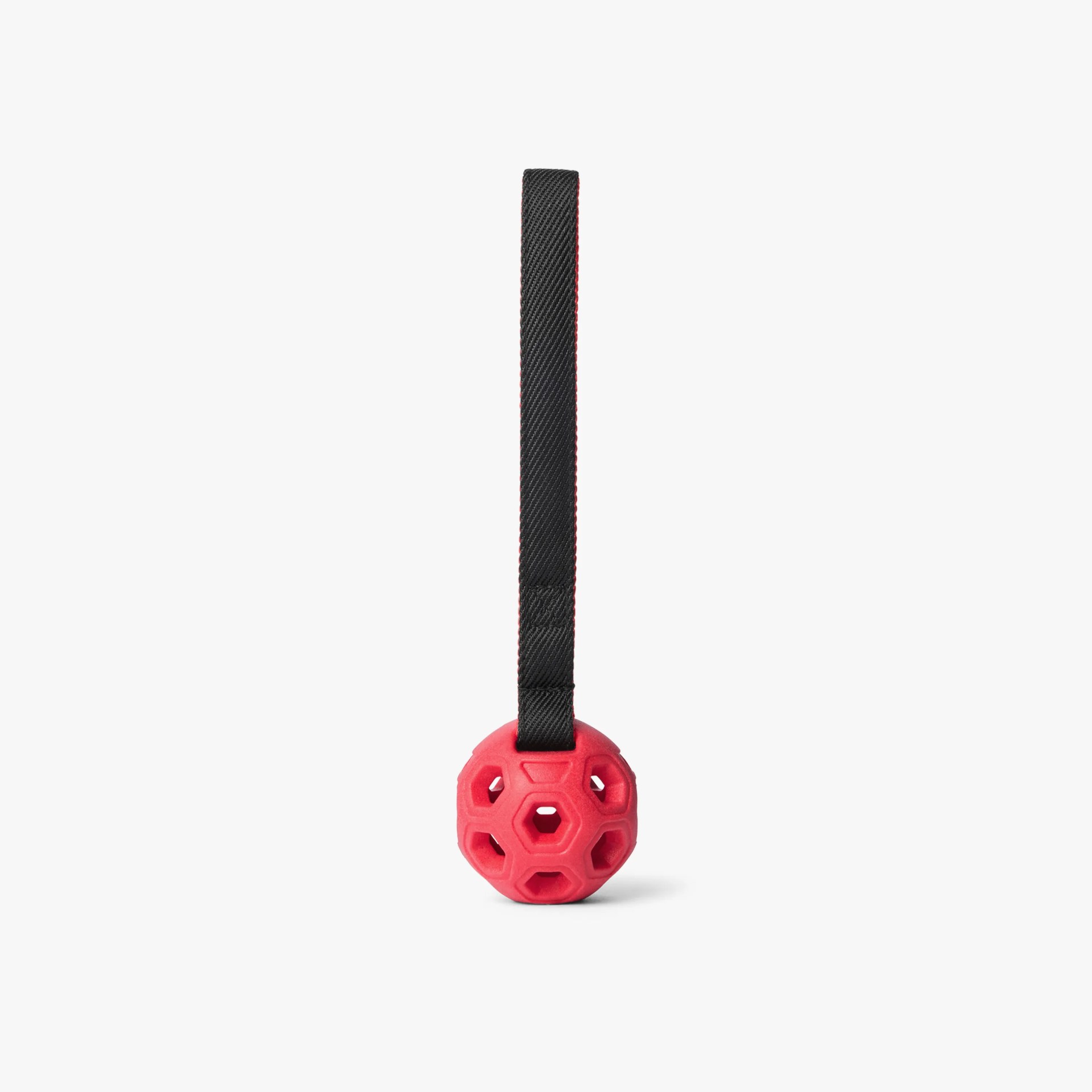 Red hollow rubber ball with hexagonal cutouts attached to a black fabric loop.