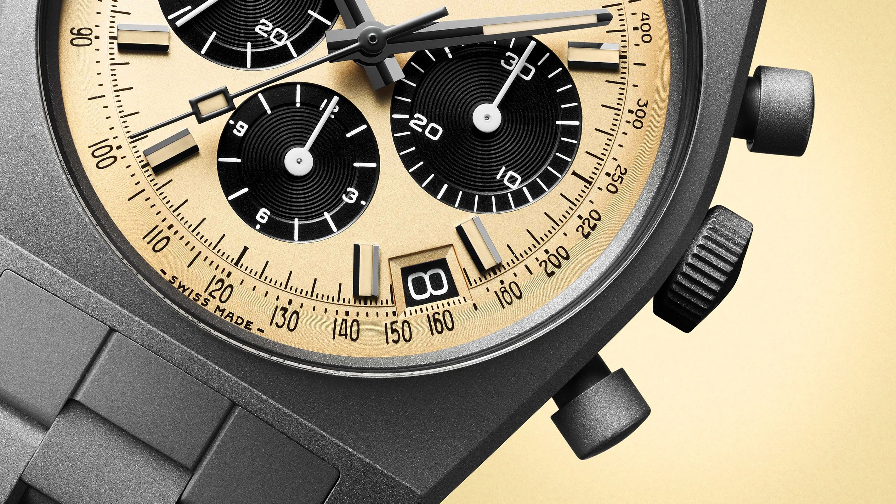 Close-up of a black chronograph watch with a beige dial, black subdials, date window, and textured pushers.