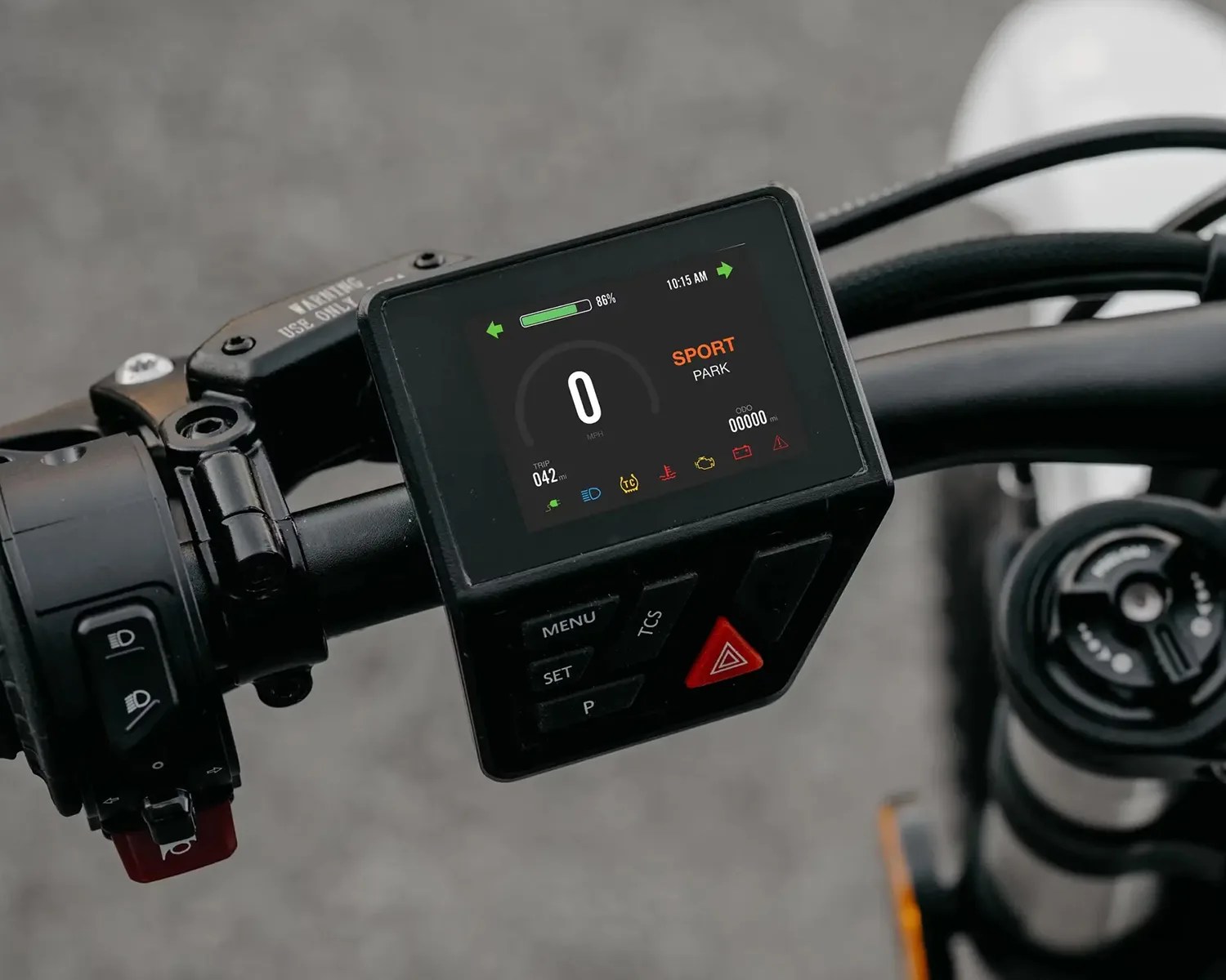 Motorcycle handlebar with digital display showing speed, mode, battery level, and control buttons.