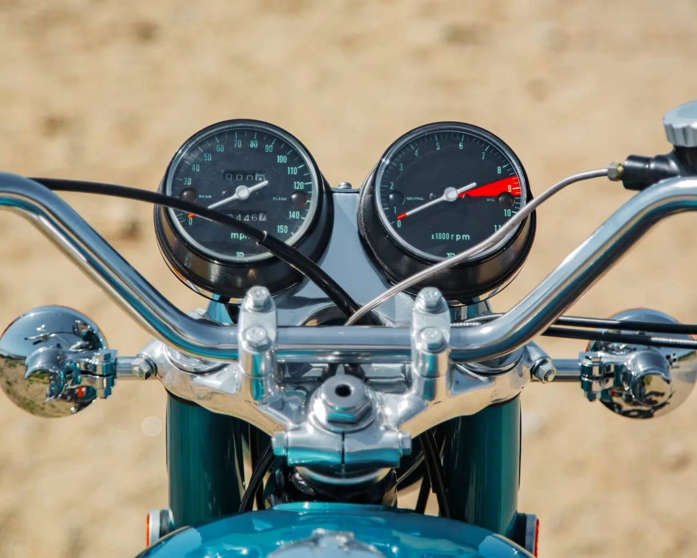Close-up of a motorcycle's chrome handlebars with speedometer and tachometer gauges.