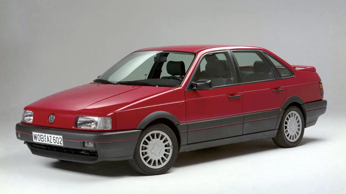 Red Volkswagen sedan with black lower trim and silver multi-spoke wheels on a plain background.