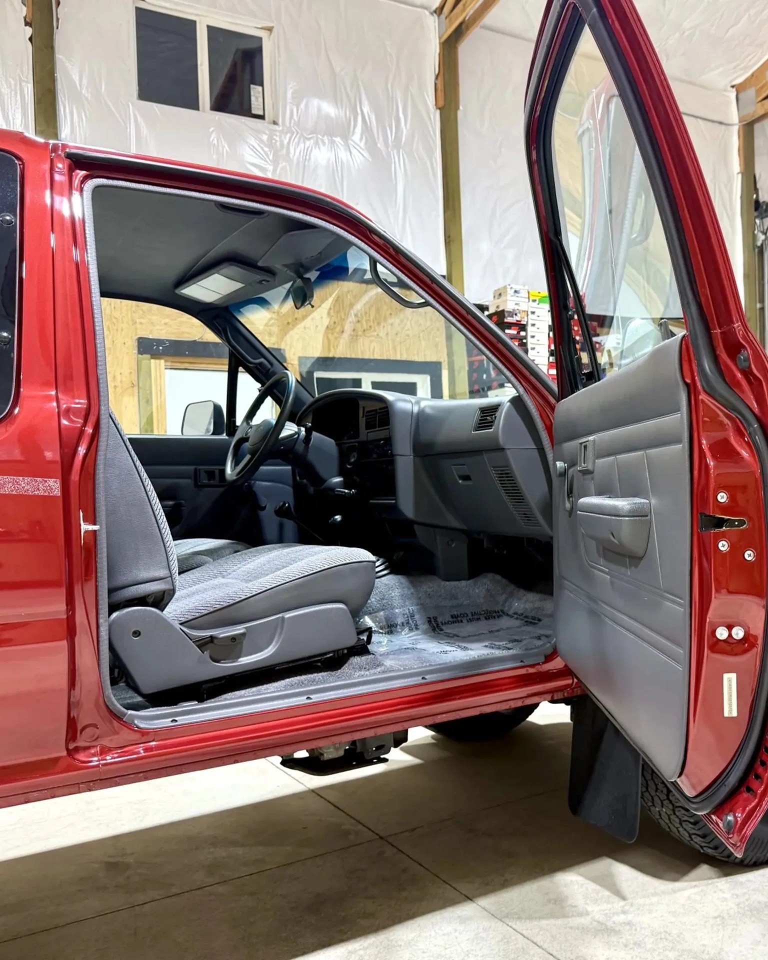 Open red truck door showing gray fabric front seat and gray interior panel with handle.