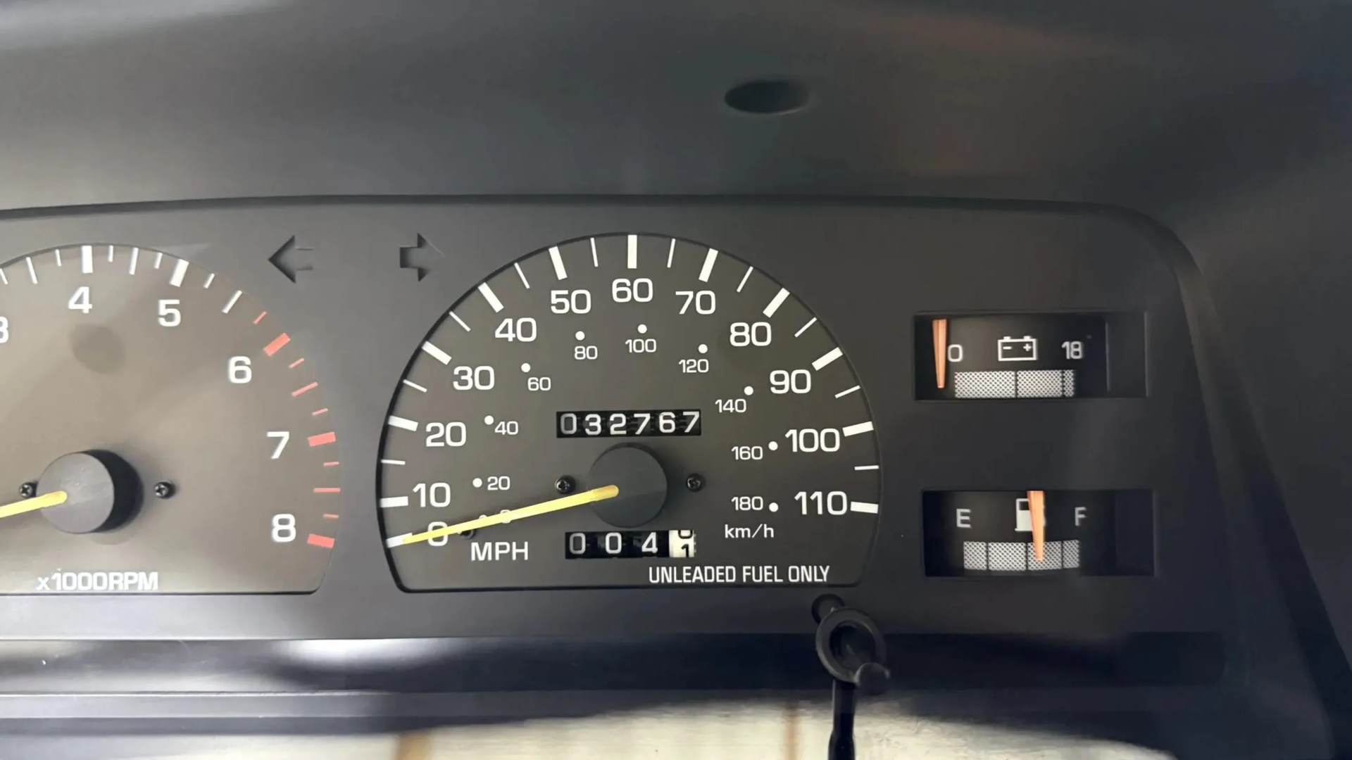 Car dashboard showing speedometer at 0 MPH, odometer reading 032767, fuel gauge near full, and battery indicator.