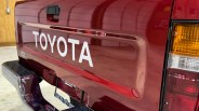 Rear end of a red Toyota truck with white "TOYOTA" lettering and V6 badge on the tailgate.