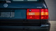 Rear view of a black Volkswagen car showing the VW logo, VR6 badge, and red and amber tail lights.