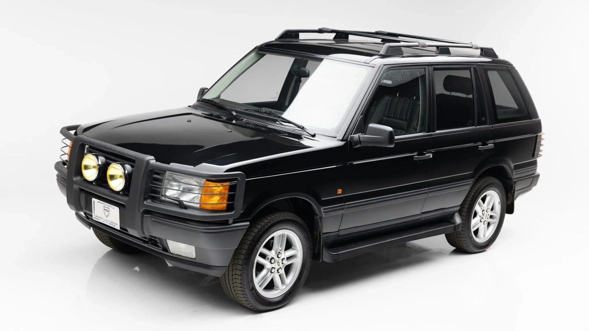 Black Range Rover SUV with roof rack, bull bar, and yellow fog lights on a white background.