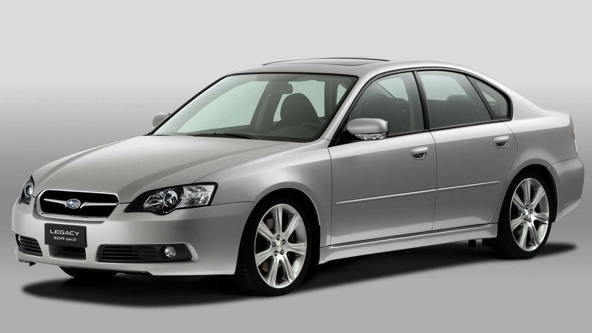 Silver Subaru Legacy sedan with alloy wheels on a gray background.