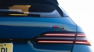 Rear view of a blue BMW M5 showing the M5 badge and illuminated taillights.