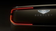 Rear close-up of a Bentley car with illuminated red taillights and glowing Bentley logo on a dark background.