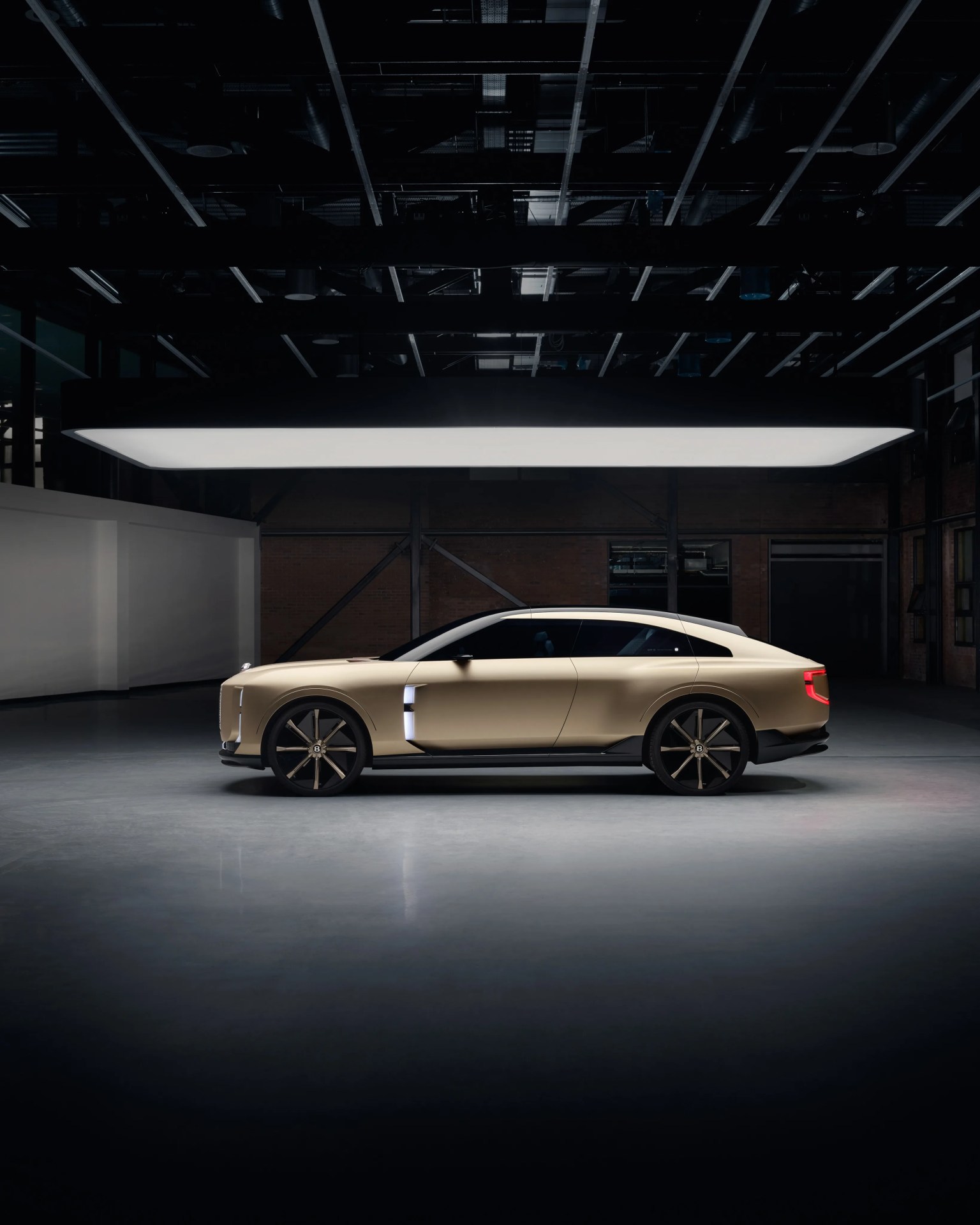 Matte gold luxury electric SUV with black wheels and tinted windows in a dimly lit industrial space.