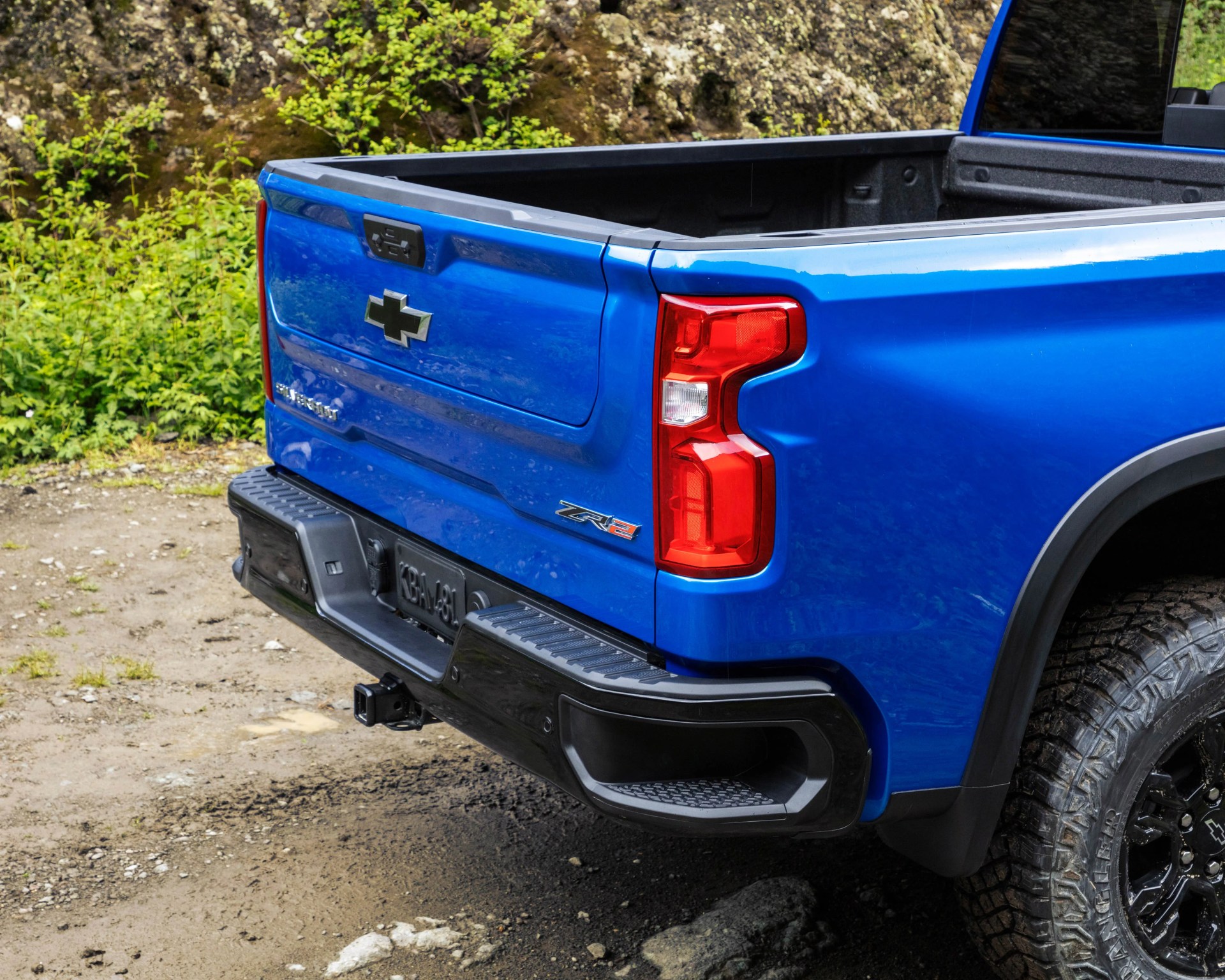 Rear corner of a blue Chevrolet Silverado ZR2 pickup truck with black bumper and off-road tires.
