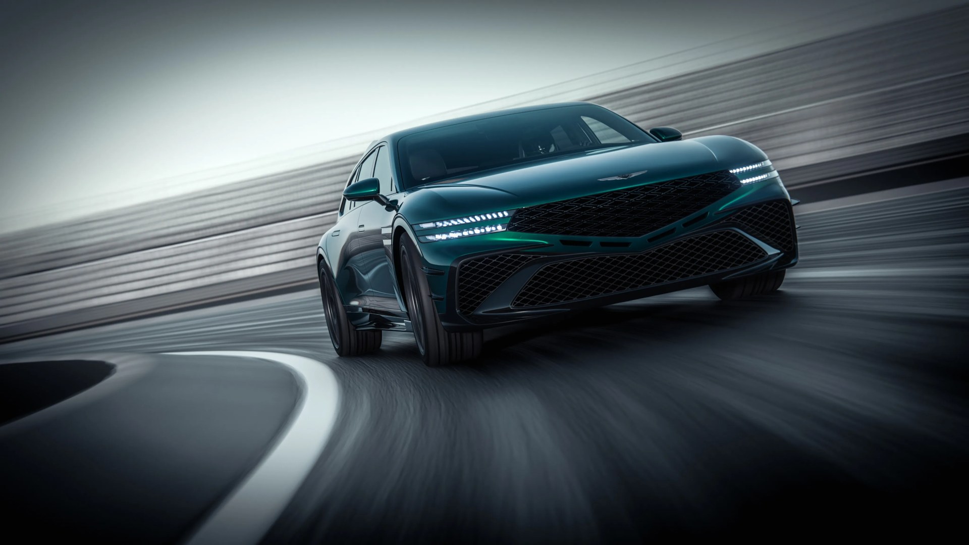 Dark green luxury sedan with LED headlights driving on a curved racetrack.