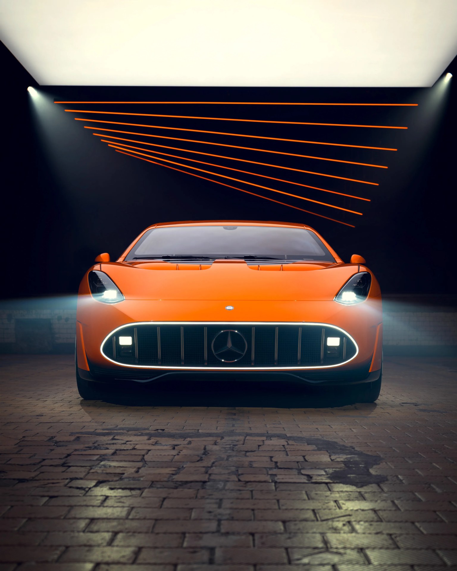 Front view of an orange Mercedes-Benz sports car with headlights on in a dark room with orange ceiling lights.
